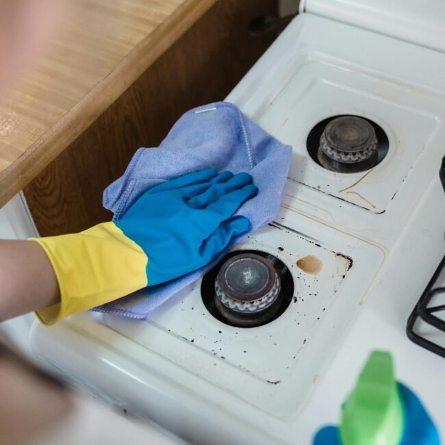 A person cleaning a gas stove