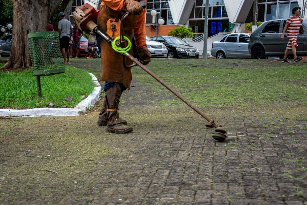 Groundskeeper trimming grass in londrina square