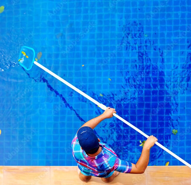 young adult man, personnel cleaning the pool from leaves